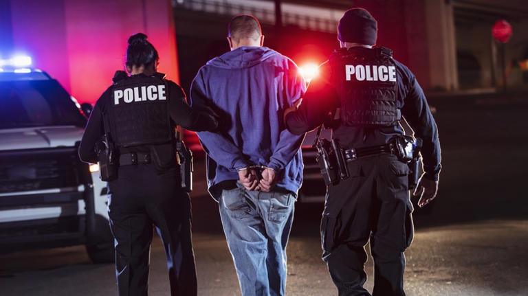 Police officer reviewing arrest warrant documents in legal setting